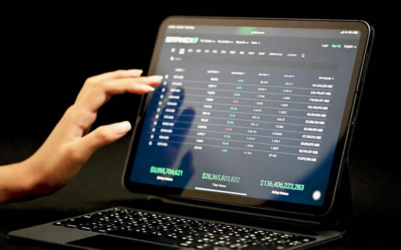 woman touching laptop screen showing trading chart
