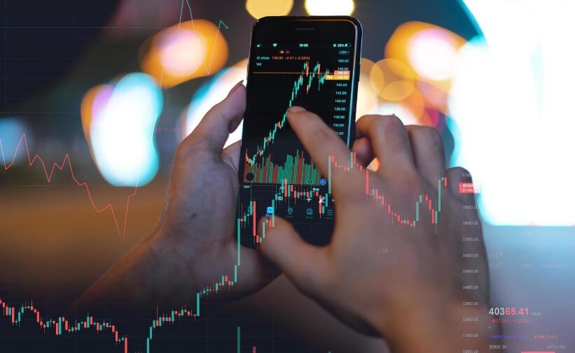 hand holding out phone taping on screen showing trading chart