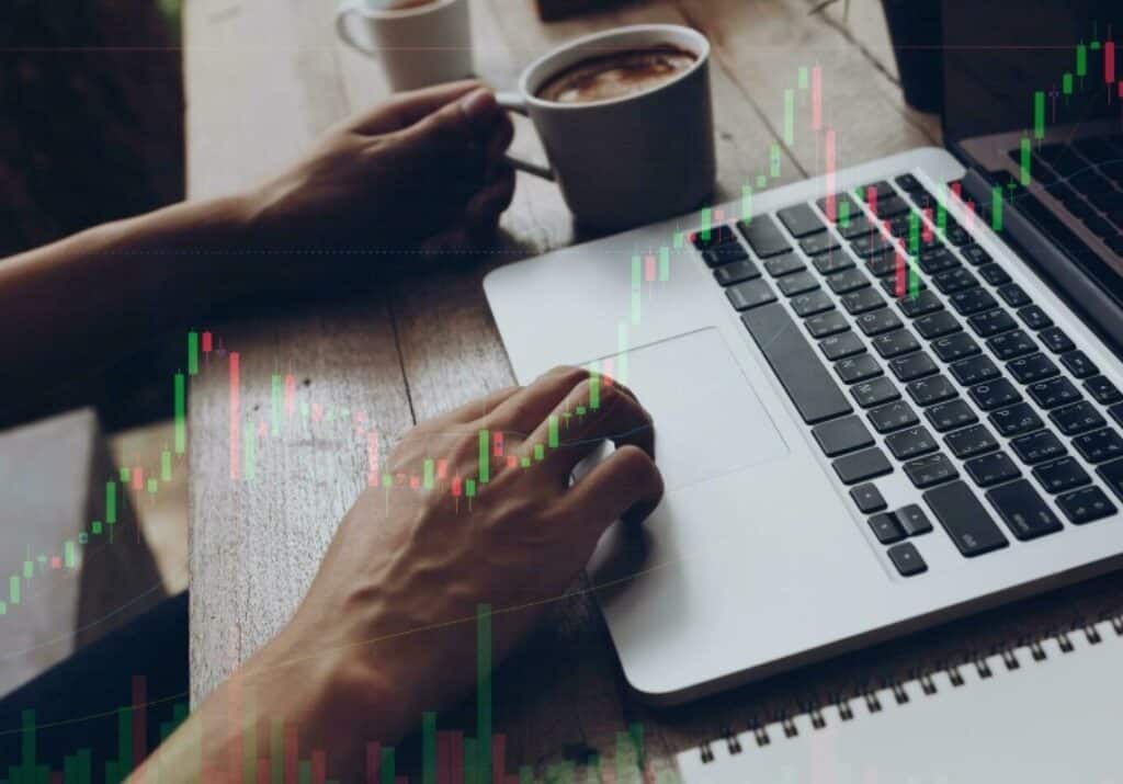 hand on laptop with forex chart overlay